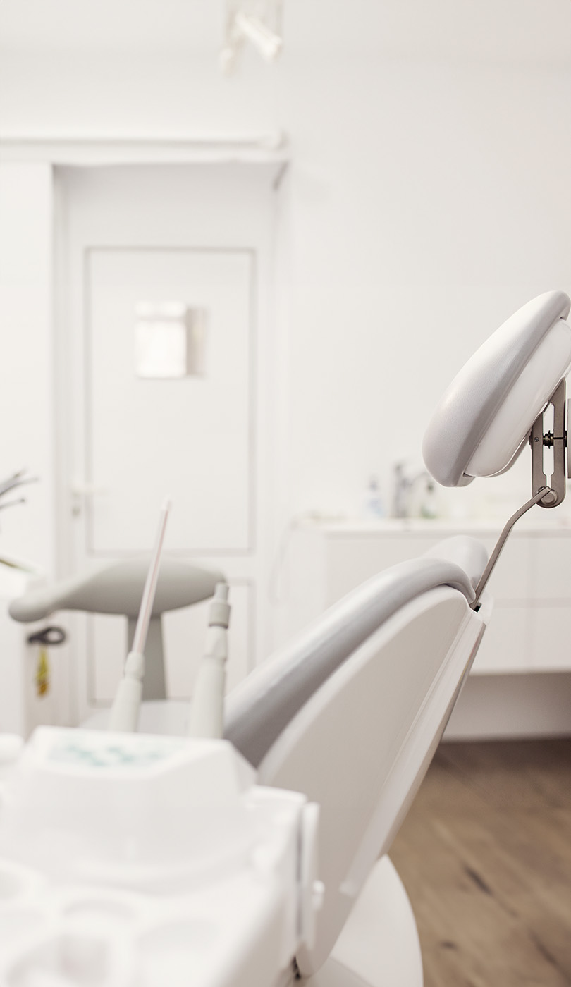 The image shows a modern dental or medical office interior with a dental chair, equipment, and a clean, professional environment.
